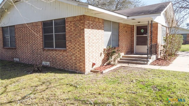 exterior space featuring brick siding, crawl space, and a lawn