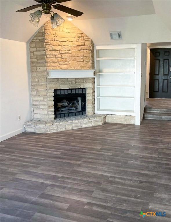 195 Gallagher Dr Unit 18, Canyon Lake, TX 78133 - unfurnished living room with a ceiling fan, visible vents, a stone fireplace, and wood finished floors