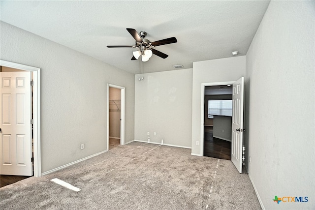 475 Autumn Leaf Dr, New Braunfels, TX 78130 - unfurnished bedroom with a walk in closet, carpet floors, a ceiling fan, and a textured ceiling