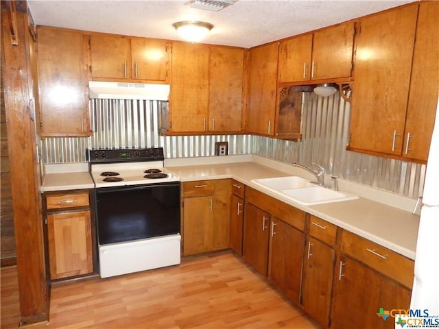 kitchen with sink, white appliances, a textured ceiling, and light hardwood / wood-style floors