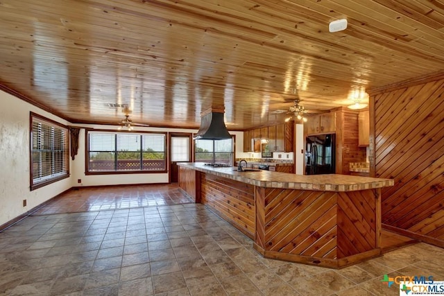 kitchen featuring black appliances, wooden walls, wooden ceiling, and island range hood