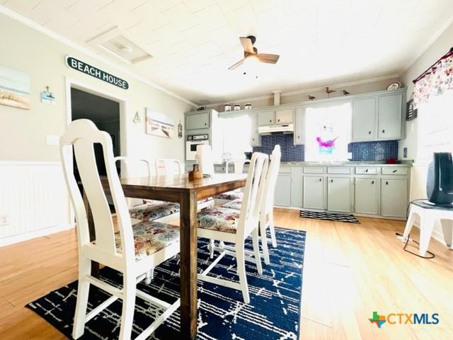 dining space with ceiling fan, ornamental molding, and light wood-type flooring