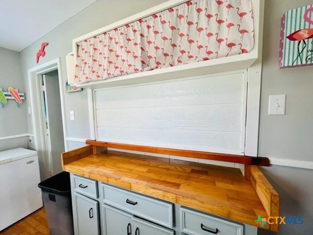 interior space featuring refrigerator, butcher block counters, and gray cabinetry