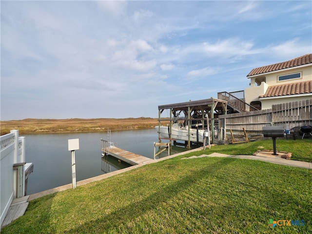 view of dock with a lawn and a water view