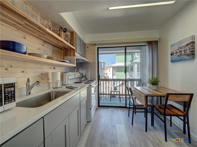 kitchen featuring sink, light stone countertops, gray cabinetry, light wood-type flooring, and electric range