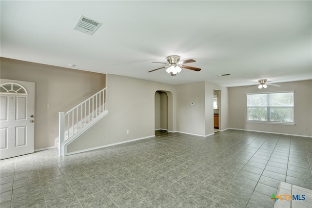 1335 Lakeside Loop, Round Rock, TX 78665 - unfurnished living room with a ceiling fan, arched walkways, stairs, and tile patterned flooring