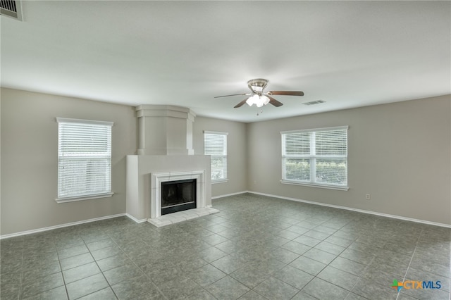 1335 Lakeside Loop, Round Rock, TX 78665 - unfurnished living room featuring ceiling fan, healthy amount of natural light, a fireplace with raised hearth, and tile patterned flooring