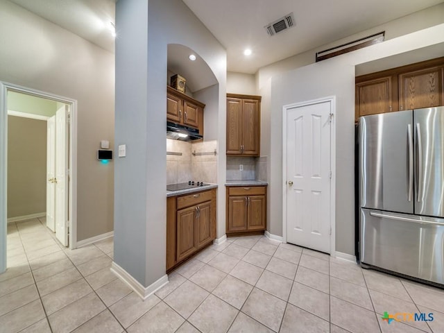 2615 Foresthaven Dr, New Braunfels, TX 78132 - kitchen featuring freestanding refrigerator, light tile patterned flooring, brown cabinetry, backsplash, and recessed lighting