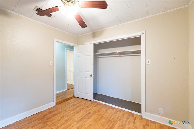 unfurnished bedroom with ornamental molding, light hardwood / wood-style floors, ceiling fan, and a closet