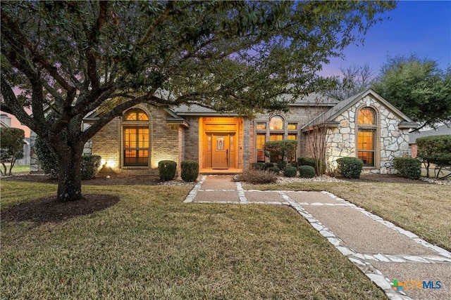 view of front of property featuring stone siding and a front lawn