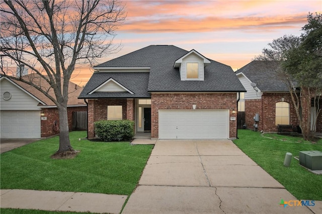 traditional-style home with brick siding, a shingled roof, concrete driveway, a front yard, and a garage