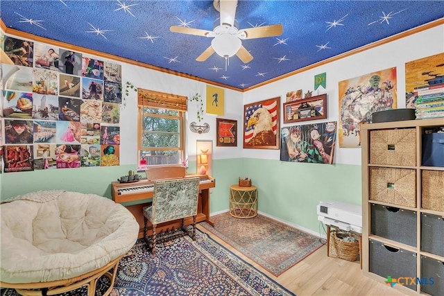 living area with ceiling fan, ornamental molding, and hardwood / wood-style floors