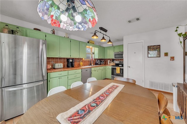 kitchen with a textured ceiling, appliances with stainless steel finishes, decorative backsplash, sink, and green cabinetry