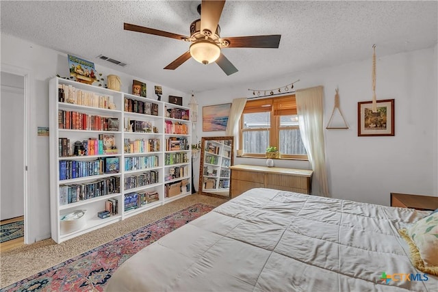 carpeted bedroom with ceiling fan and a textured ceiling