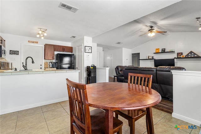 tiled dining room with vaulted ceiling, ceiling fan with notable chandelier, and sink