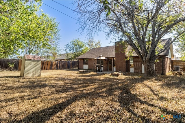 rear view of property with central air condition unit and a storage unit