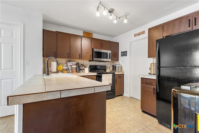 kitchen featuring kitchen peninsula, backsplash, sink, black appliances, and light tile patterned flooring