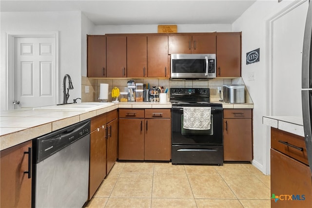 kitchen featuring backsplash, sink, light tile patterned flooring, and stainless steel appliances