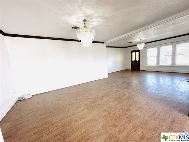 unfurnished living room with wood-type flooring, a textured ceiling, a chandelier, and crown molding