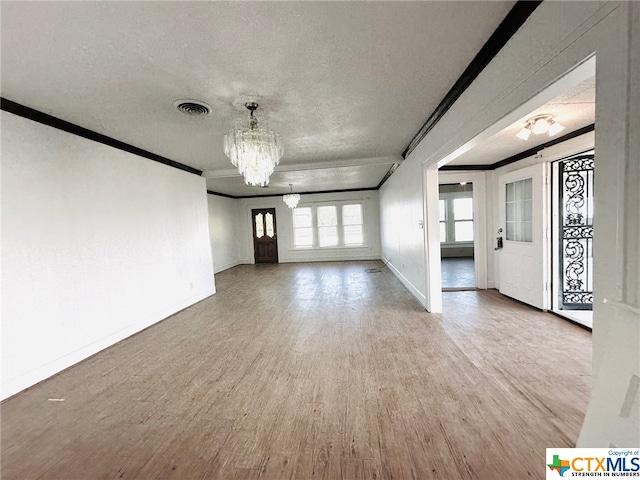 unfurnished living room with a textured ceiling, wood-type flooring, a chandelier, and crown molding