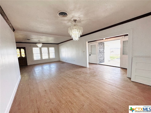 unfurnished living room featuring a chandelier, a textured ceiling, hardwood / wood-style flooring, and ornamental molding