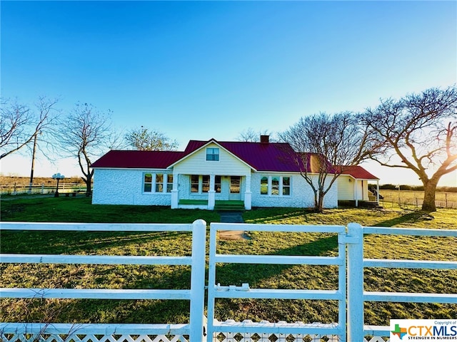 view of front of property featuring a front lawn, fence private yard, a chimney, and metal roof