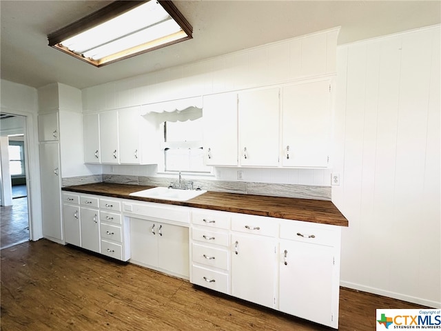 kitchen featuring dark wood-type flooring, butcher block counters, sink, and white cabinets