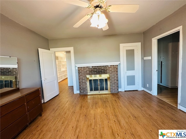 unfurnished living room with light wood-type flooring, ceiling fan, and a fireplace