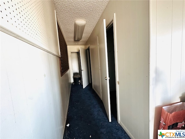 corridor featuring wood walls and a textured ceiling