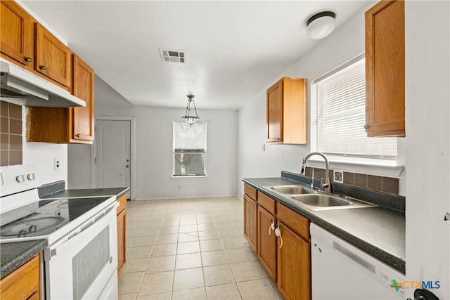 kitchen with light tile patterned floors, white appliances, decorative light fixtures, and sink