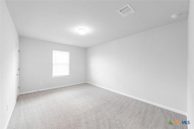 empty room featuring visible vents, baseboards, and carpet