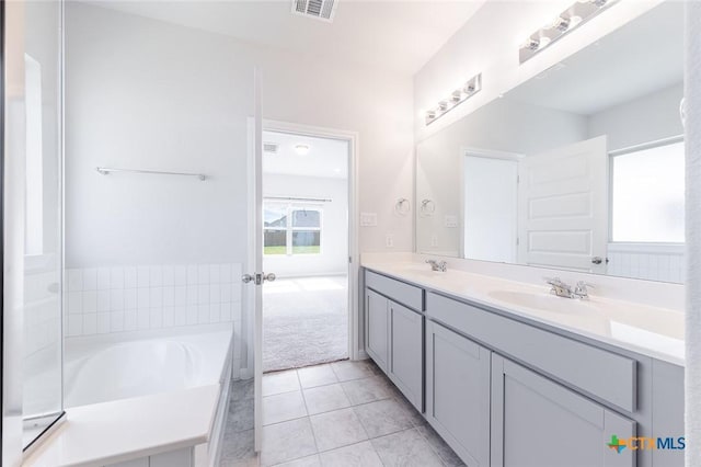 bathroom with tile patterned floors, visible vents, a sink, double vanity, and a bath