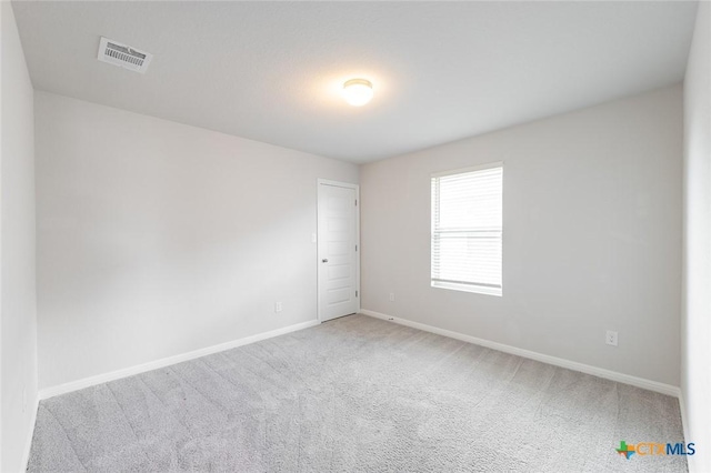 carpeted spare room with visible vents and baseboards