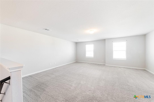 carpeted spare room featuring visible vents, baseboards, and a textured ceiling