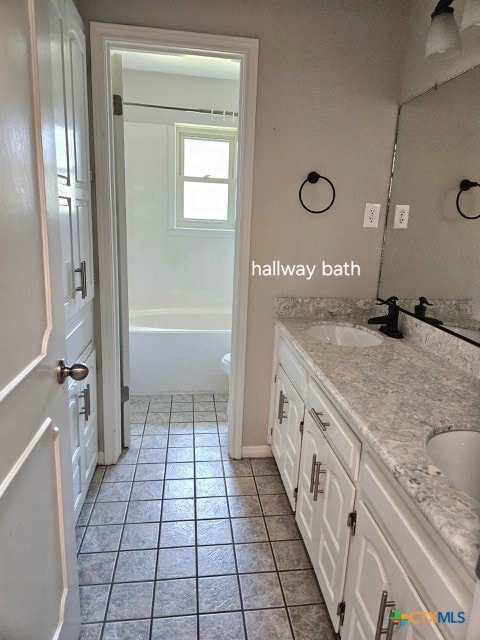 full bathroom with a sink, double vanity, tile patterned flooring, and a tub