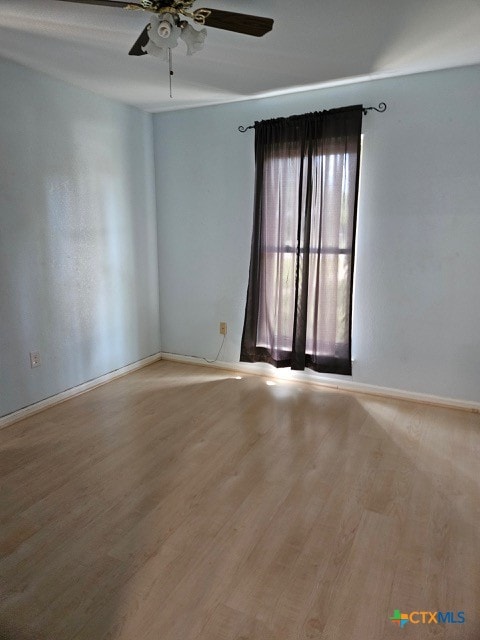 empty room with wood finished floors, baseboards, and a ceiling fan