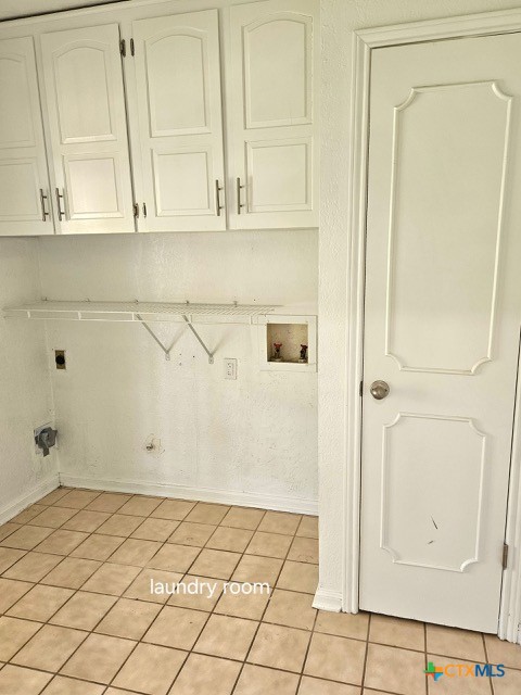 washroom with hookup for an electric dryer, hookup for a washing machine, cabinet space, and light tile patterned floors