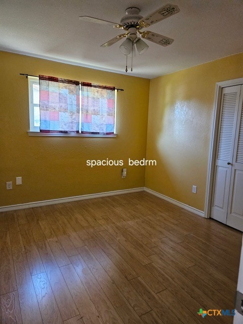 empty room featuring baseboards, a ceiling fan, and wood finished floors