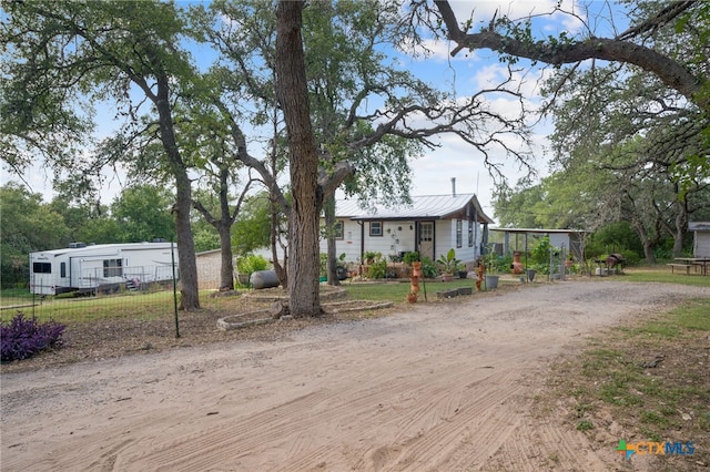 manufactured / mobile home featuring fence, metal roof, and dirt driveway