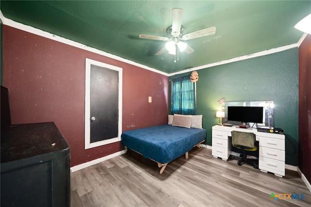 bedroom featuring baseboards, a textured wall, a ceiling fan, and wood finished floors