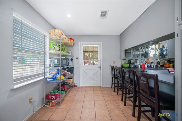 interior space with tile patterned flooring, backsplash, and visible vents