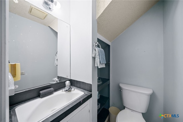 half bathroom featuring vanity, a textured ceiling, vaulted ceiling, and toilet
