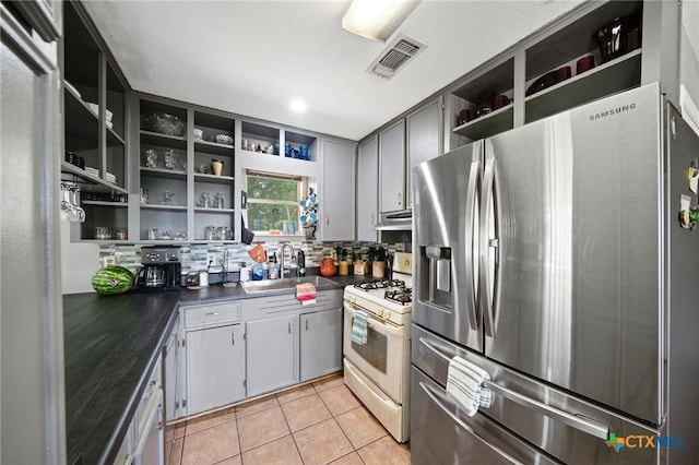 kitchen featuring open shelves, a sink, stainless steel fridge with ice dispenser, white gas stove, and visible vents