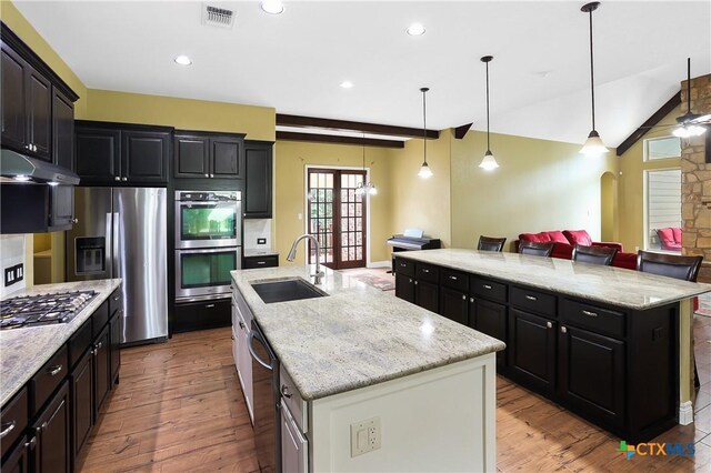 335 Mill Run, New Braunfels, TX 78132 - kitchen featuring appliances with stainless steel finishes, a large island with sink, under cabinet range hood, wood finished floors, and open floor plan