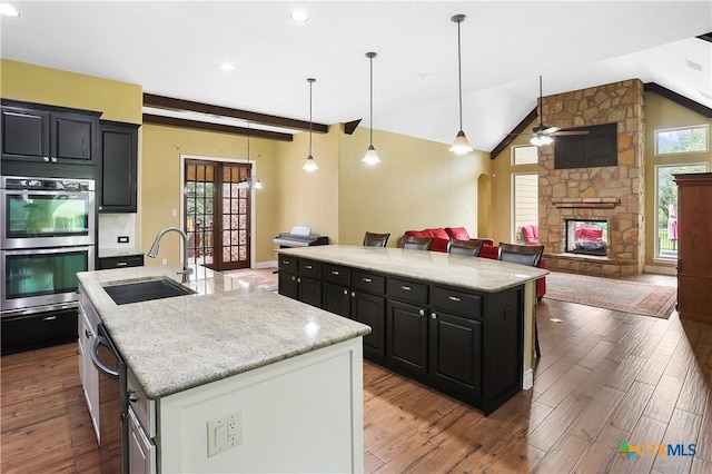 335 Mill Run, New Braunfels, TX 78132 - kitchen with double oven, a center island with sink, dark cabinetry, wood finished floors, and recessed lighting