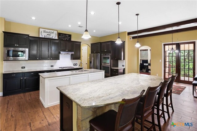 335 Mill Run, New Braunfels, TX 78132 - kitchen with appliances with stainless steel finishes, an island with sink, arched walkways, dark wood finished floors, and recessed lighting