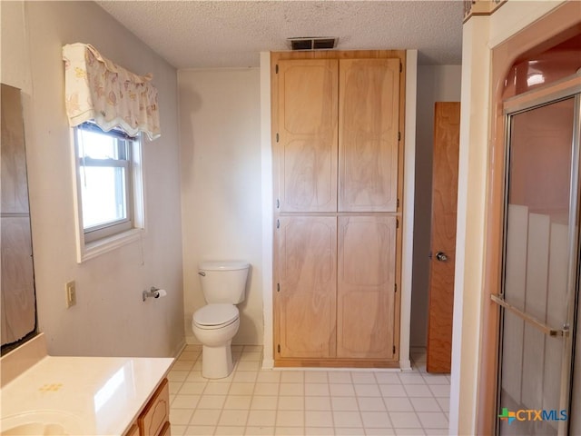 bathroom with a textured ceiling, toilet, a shower with shower door, and vanity