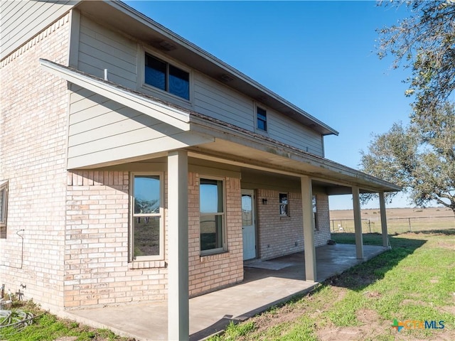 rear view of property featuring a lawn and a patio