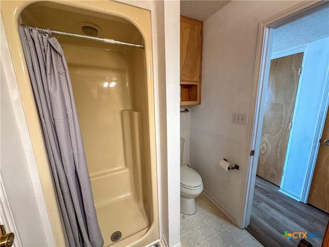 bathroom with a textured ceiling, a shower with shower curtain, and toilet