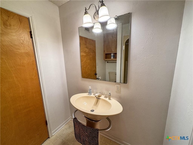 bathroom with toilet, sink, and a chandelier